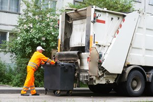 A worker putting the bin on a collection vehicle 